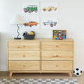 Natural wood six-drawer dresser in kids' bedroom with toy cars and wooden organizer, woven storage basket, modern lamp, car-themed wall art and soccer ball — children's room storage and decor