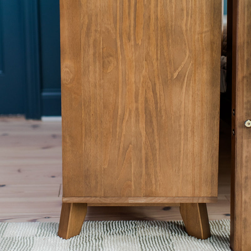 Mid-century modern solid wood cabinet with tapered legs on a textured rug, light hardwood floor and dark blue wall background