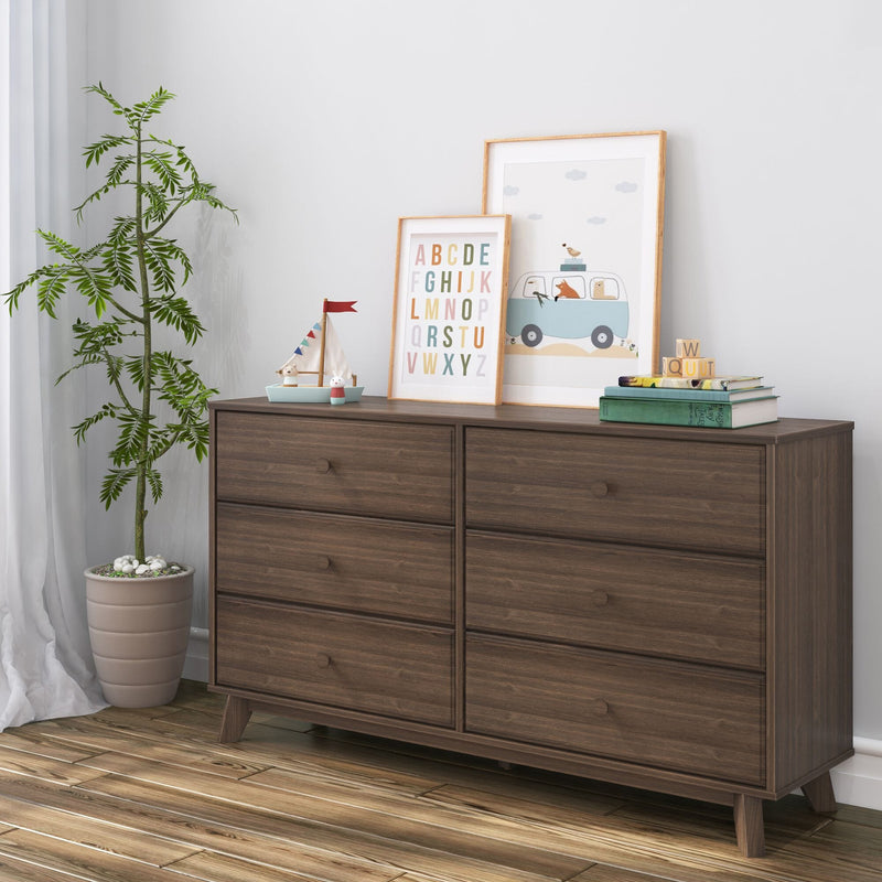 Wooden dresser with six drawers, decorative artwork, and potted plant in modern living room setting.