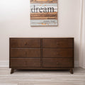 Mid-century modern six-drawer brown walnut dresser in minimalist bedroom with hardwood floor and "dream" inspirational wall art