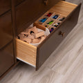 Open dark wood dresser drawer in child's room with wooden building blocks in a rope basket and divided toy car organizer on light laminate floor