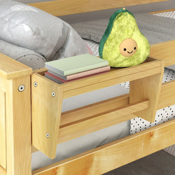 Cuddly avocado-shaped plush toy and stack of books on wooden bed shelf with polka-dot bedding.