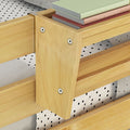 Close-up of natural pine wood bunk bed safety rail with visible recessed screw hardware, natural wood finish, polka dot bedding and stacked pastel notebooks, children's bedroom furniture detail