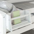 White wooden kids bunk bed with built-in ladder bookshelf holding a pastel green book, polka-dot sheets and gray pillow — modern space-saving children's bedroom storage solution