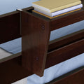 Close-up of dark wood bunk bed guardrail and ladder corner with blue bedding and stacked books on upper bunk