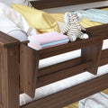 Dark walnut wooden bunk bed side shelf with built-in storage holding a striped elephant plush toy and stacked pastel books, yellow pillow and cozy bedding in a child's bedroom
