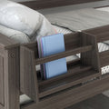 Wooden bunk bed with built-in bedside bookshelf holding blue and purple hardcover books, gray polka-dot sheets, and a white pillow
