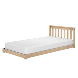 Wooden single bed frame with slatted headboard and plain white mattress.