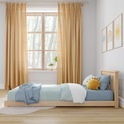 Cozy kids' bedroom with sunlight coming through a window, featuring a wooden bed, blue striped bedding, and cheerful wall art.