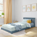 Bright modern children's bedroom with blue toddler bed, striped teal bedding, smiling sun plush, pastel rainbow and cloud nursery wall art, beige curtains and natural light