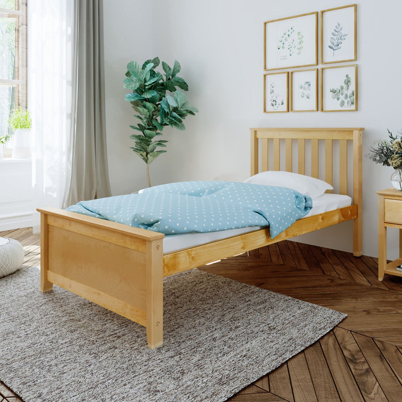 Natural wood bed frame with a blue polka dot comforter in a cozy bedroom with wooden flooring and plant decor.