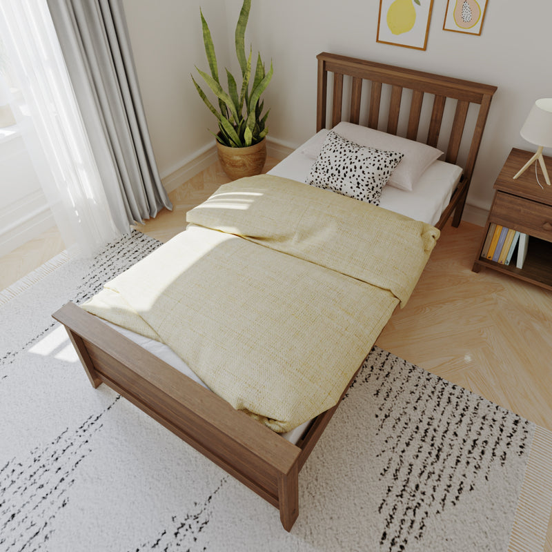 Cozy bedroom with wooden bed frame, yellow bedding, and decorative pillows in a sunlit modern space.