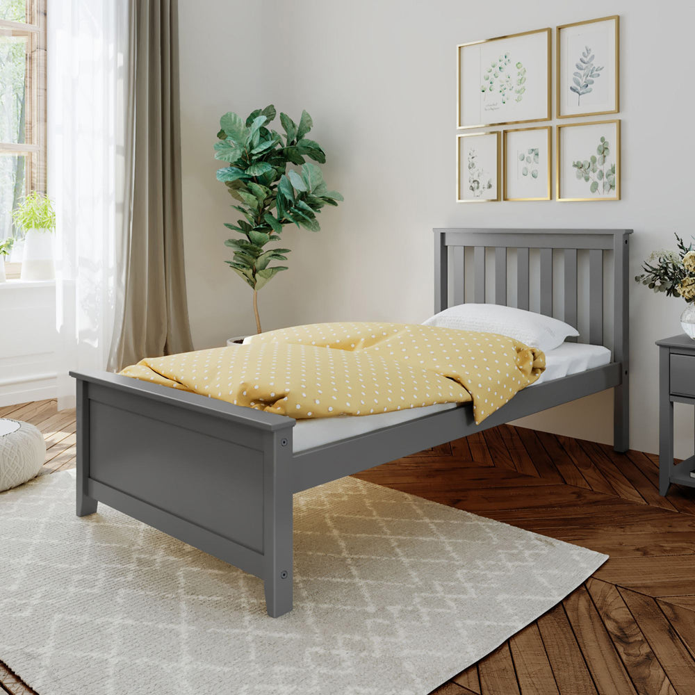 Gray wooden single bed with yellow polka dot bedding in modern bedroom with plant and wall art.