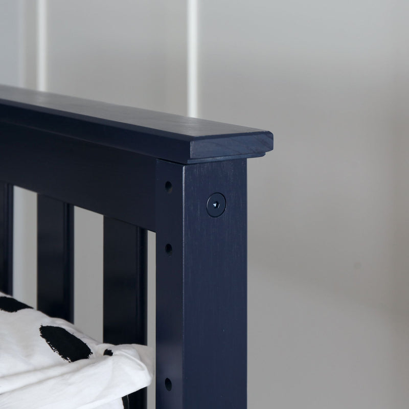 Close-up of a dark blue wooden bed frame showing edge details and pillow fabric pattern.
