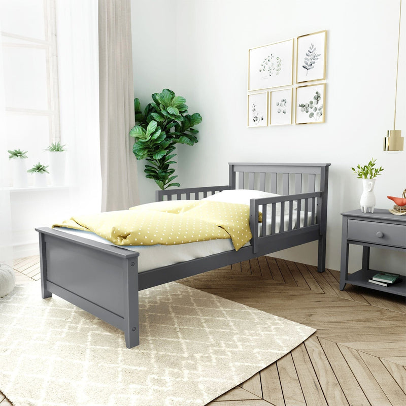 Gray wooden bed frame in stylish bedroom with yellow polka dot blanket and green plant decor.