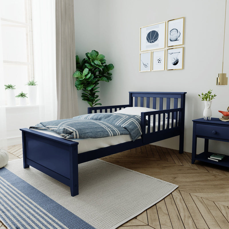 Navy blue wooden toddler bed with guard rails and blue-striped duvet in modern kids bedroom with potted plant and matching navy nightstand