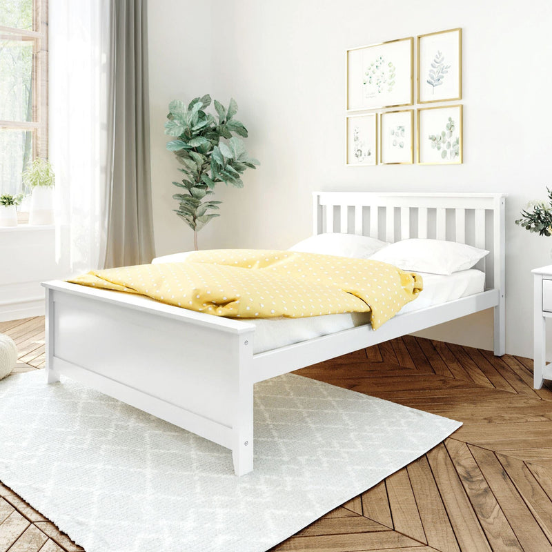 White wooden bed frame with yellow polka dot blanket in bright, minimalist bedroom with green plant and framed artwork on the wall.