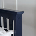 Close-up of navy blue wooden bed headboard corner with visible screw and black-and-white duvet, modern bedroom decor