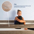 Smiling girl sitting on a bed with a clay gray-brown wire‑brushed wood frame and white constellation wallpaper, inset close-up of multi-layered clay wood texture