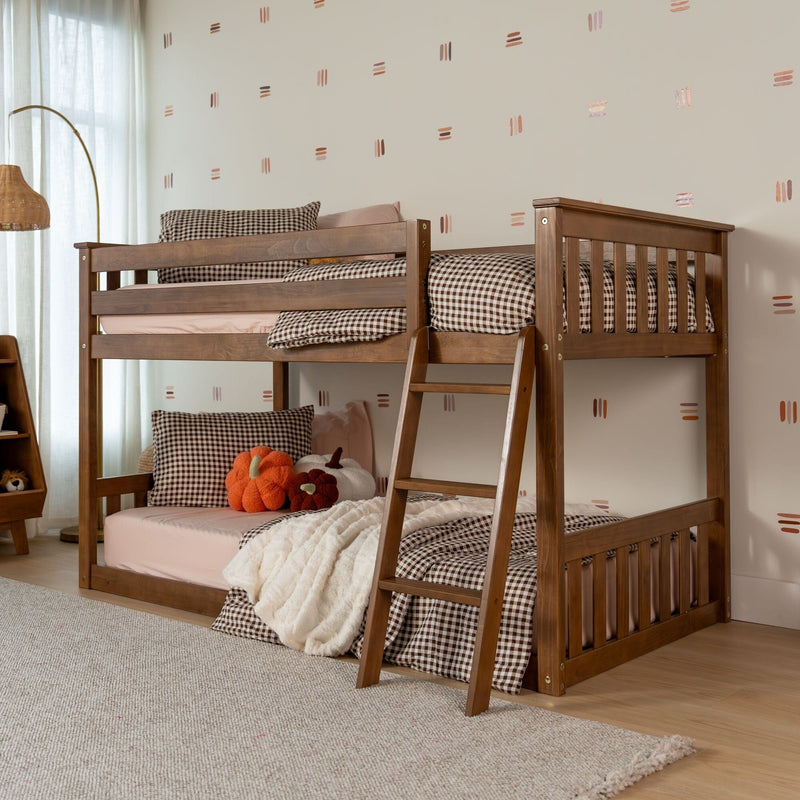 Cozy wooden bunk bed with ladder in children's bedroom, brown gingham bedding, pink sheets, plush pumpkin toys, and modern neutral decor