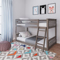 Modern gray wooden twin-over-twin bunk bed with ladder in a kids' bedroom, polka-dot bedding, pastel animal wall art, light blue curtains, colorful geometric area rug and pink knitted pouf