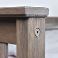 Close-up of rustic gray-stained wooden bed frame post with visible hex bolt, pronounced wood grain texture and joinery detail