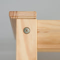 Close-up of light pine furniture corner joint with exposed hex bolt and visible wood grain, furniture assembly detail