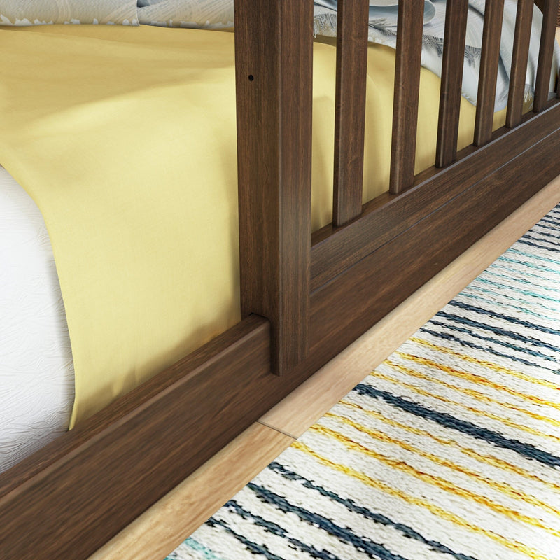 Wooden bed frame with yellow bedding and striped rug in a cozy bedroom setting.