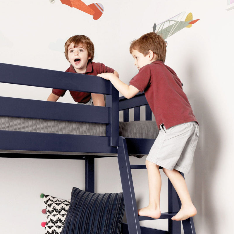 Two young children playing on a navy blue bunk bed in a room decorated with airplane wall decals.