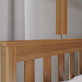 Close-up of modern oak wooden headboard and slatted bed frame with neutral textured curtain and wooden bedside lamp in minimalist bedroom