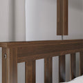 Dark wood slatted headboard with modern wooden bedside lamp and neutral textured curtain in a minimalist bedroom