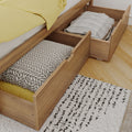 Wooden under-bed storage drawers open with folded blankets and patterned pillows, yellow bedding and textured rug on hardwood floor