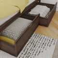 Under-bed storage drawers in dark wood platform bed holding pillows and blankets — space-saving bedroom storage solution on hardwood floor with patterned rug