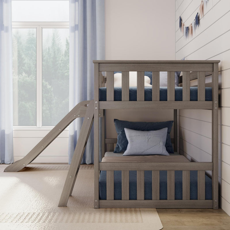 Modern gray wooden bunk bed with slide in bright kids bedroom, navy blue bedding and pillows, large window and neutral farmhouse decor