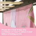 Pink kids princess bed canopy curtain with gold trim hung from a wooden bed frame using a hook-and-loop strip, showing instruction to allow adhesive strip 1 hour to adhere before attaching curtain