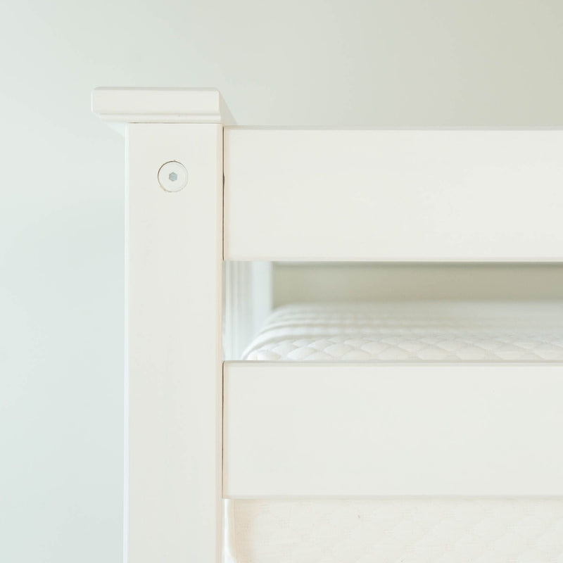White bunk bed frame with comfortable mattress in minimalistic bedroom setting.