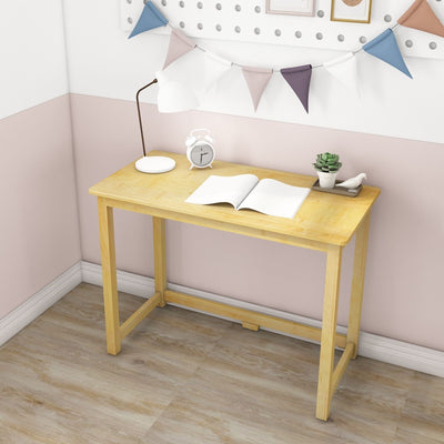 Minimalist light wood writing desk in a pastel pink corner with lamp, alarm clock, open notebook, small succulent and bunting flags — compact home office/study workspace