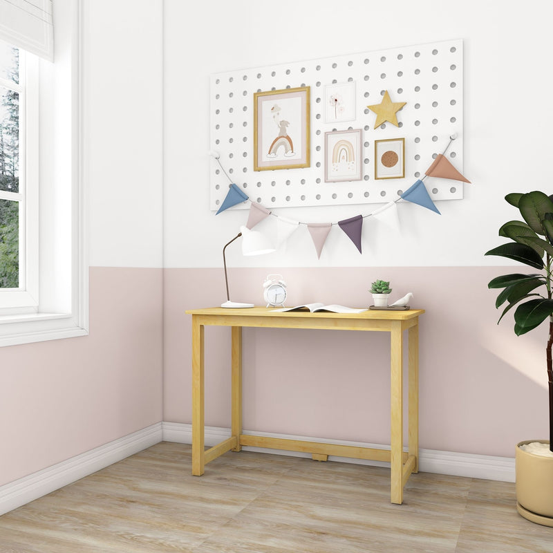 Stylish home office with wooden desk, pink and white decor, and potted plant by window.