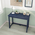 Navy blue minimalist writing desk in a bright home office corner with white desk lamp, succulent, pencil holder and small wooden house decor
