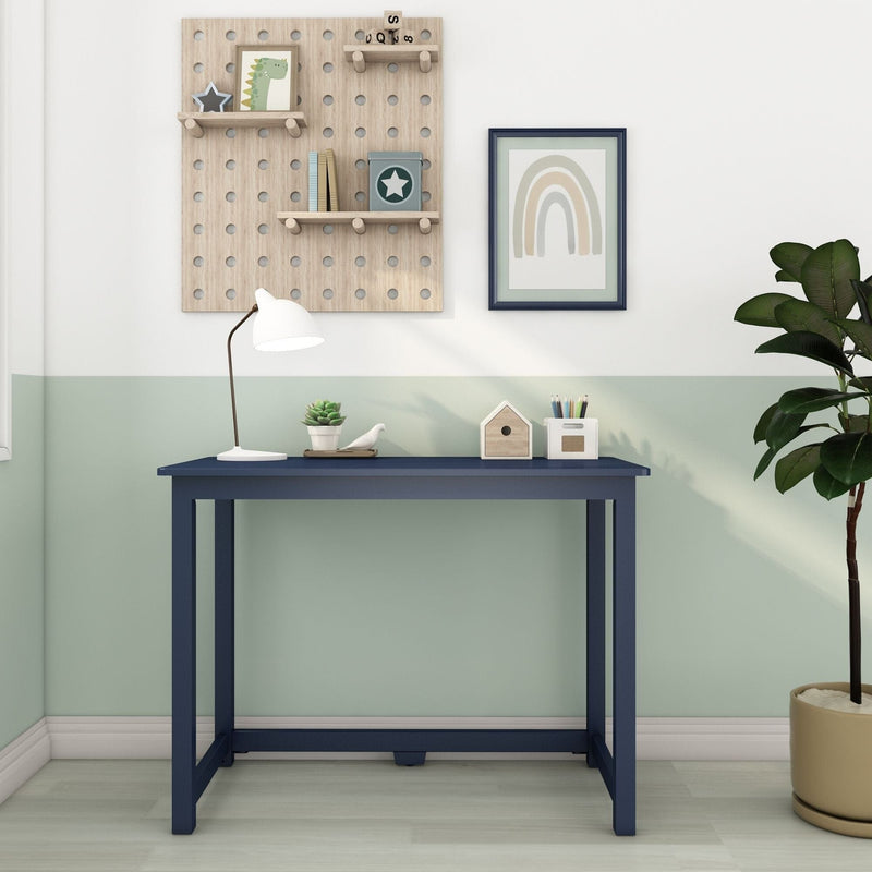 Navy blue children's desk in pastel mint nursery with pegboard shelves, white desk lamp, framed rainbow art and potted plant