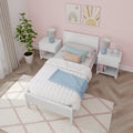 Cozy kids' bedroom with pink wallpaper, white bed frame, colorful pillows, and bedside tables.