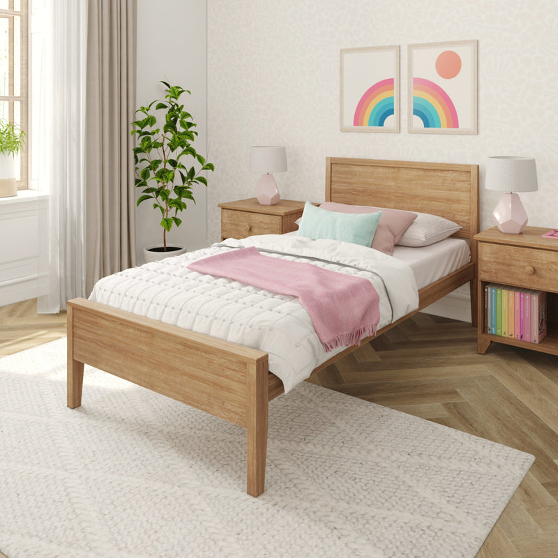 Cozy pastel bedroom with wooden bed, white textured bedding, pink throw blanket, pastel rainbow wall art, potted plant and matching bedside lamps