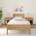 Cozy pastel children's bedroom interior with wooden bed, pink bedside lamps, rainbow framed wall art, patterned wallpaper and houseplant