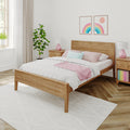 Scandinavian-style bedroom with wooden bed frame, white quilt, pink pillows and lamps, rainbow wall art, potted plant and natural light