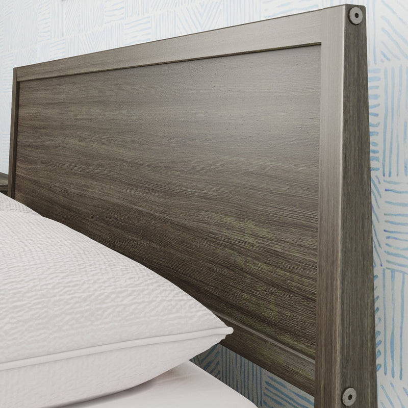 Close-up of modern gray wood headboard with textured wood grain and metal hardware beside white bedding in a contemporary bedroom