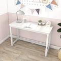 White minimalist writing desk against pink accent wall in a small home office with desk lamp, alarm clock, open notebook, succulent plant and decorative bunting on light wood floor
