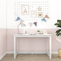 Minimalist white kids desk in a pastel pink nursery with pegboard gallery, colorful bunting, task lamp, succulent and wooden floor, children's study nook decor