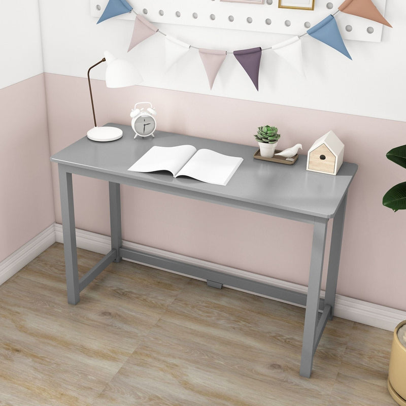 Minimalist small gray writing desk in pastel home office corner — compact study desk with open book, white lamp, alarm clock, succulent, decorative birdhouse and bunting on light wood floor