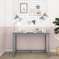 Modern pastel nursery study nook with grey desk, white desk lamp, alarm clock, open book, succulent and birdhouse on a pink-and-white wall decorated with bunting and framed rainbow art