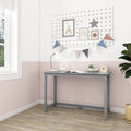 Small gray kids study desk in pastel pink-and-white nursery with pegboard gallery, colorful bunting, desk lamp, alarm clock, succulent and wooden birdhouse on light wood floor
